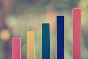 A series of coloured sticks of different height in ascending order on a blurred background